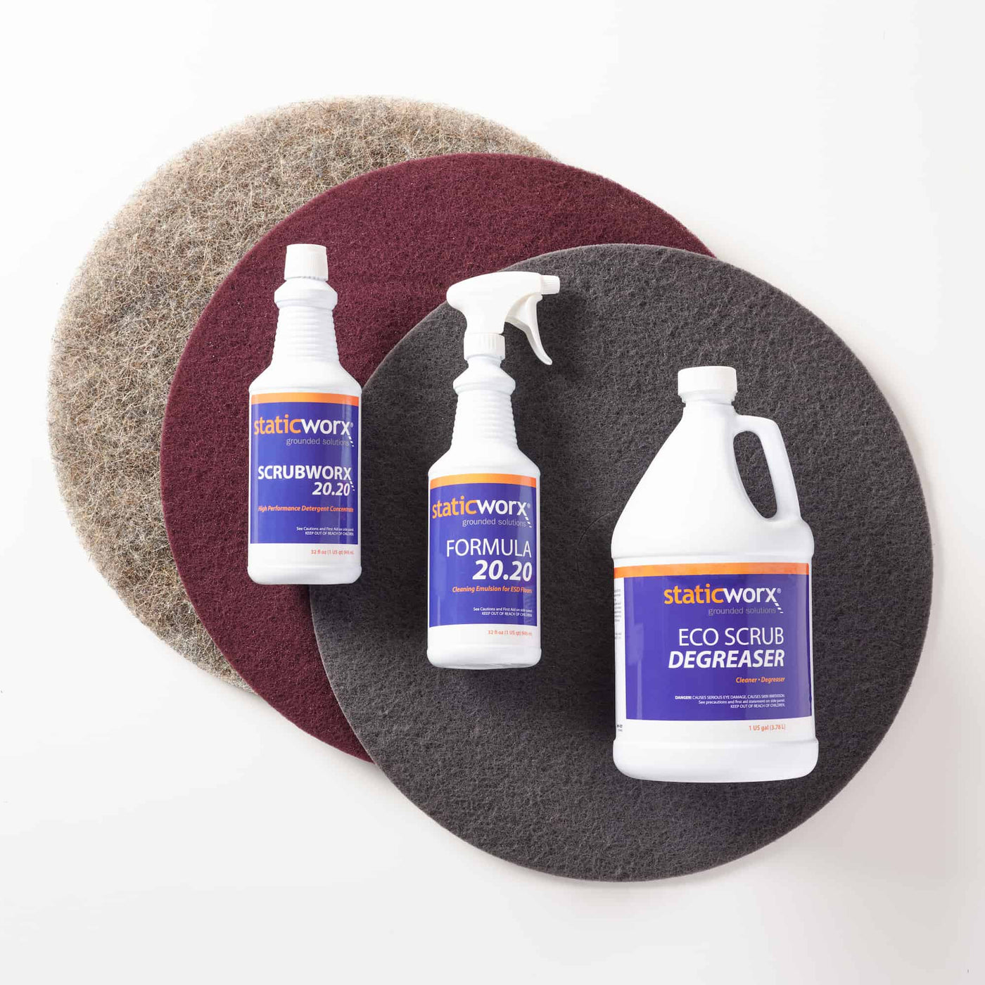 Photo of one of each scrubbing pad - grey, maroon and neutral, plus cleaning materials bottles: ScrubWorx 20.20, Formula 20.20 and EcoScrub degreaser
